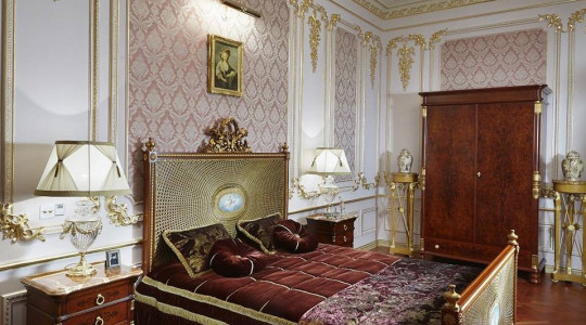 Bedroom in neoclassical style with gilded stucco molding, artsy decor and interior design Bedroom in a neoclassical style in burgundy color