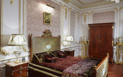 Bedroom in neoclassical style with gilded stucco molding, artsy decor and interior design Bedroom in a neoclassical style in burgundy color