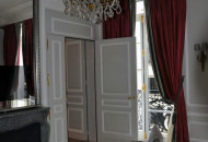 A chic chandelier framed by stucco molding emphasizes the flawless lines of the interior, and the curtains give it palace grandeur Stucco molding in the interior of the living room in gray tones