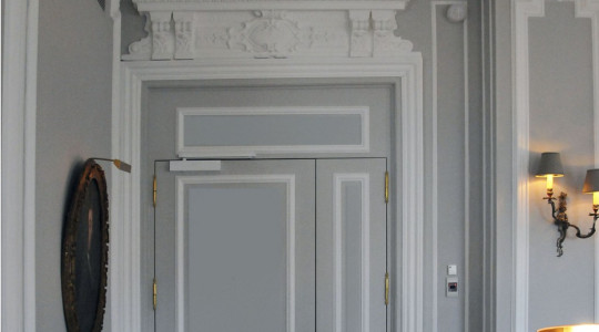 The laconic form of moldings, door trims, complemented by elegant stucco elements of the ceiling Fragment of the living room interior in gray tones with stucco decor