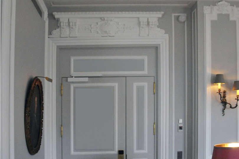 The laconic form of moldings, door trims, complemented by elegant stucco elements of the ceiling Fragment of the living room interior in gray tones with stucco decor