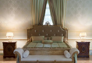 Bed in a classic style bedroom with a carved headboard, upholstered with textiles, a bedside sofa, bedside tables, decorated with veneer and gilded overlays. Gorgeous classic bed