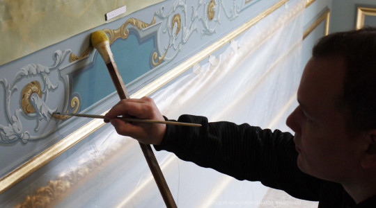 Художник выполняет роспись на стене