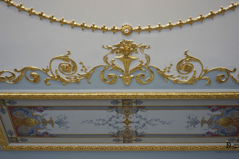 Fragment of the ceiling with painting and gilded elements Gilding and painting in a classic interior