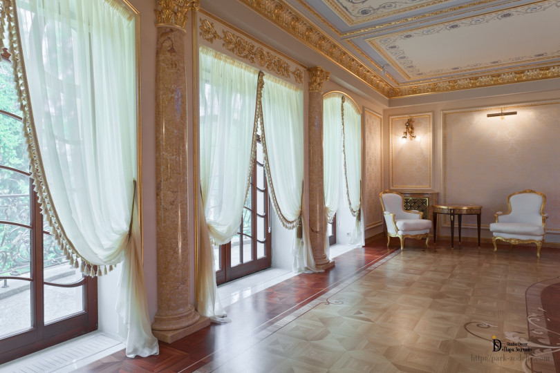 Большие окна и двери стали отправной точной создания светлого интерьера с позолоченной лепниной, мраморными полуколоннами и художественным паркетным полом Шикарная зона выхода на террасу в классическом стиле