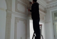 Installation of a plaster rosette for decorating the ceiling of a historic interior installation of stucco decoration on the wall