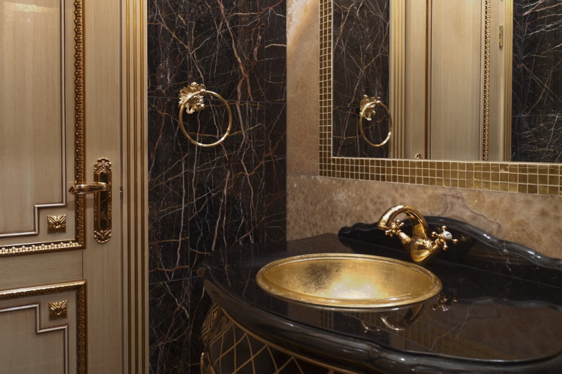 Санузел в классическом стиле оформлен мрамором двух оттенков, необычным умывальником и дверями с легким золочением Дорогой интерьер санузла декорированный мрамором